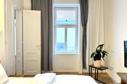 een slaapkamer met een raam en een bed met een potplant bij Green Prater City Apartment in Wenen
