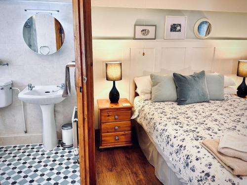 um quarto com uma cama, um lavatório e um espelho em The Old Mill Holiday Cottages, Nr Mold em Mold