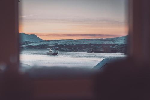 a boat in the water with a sunset in the background at Villa Havblikk Tromsø in Tromsø