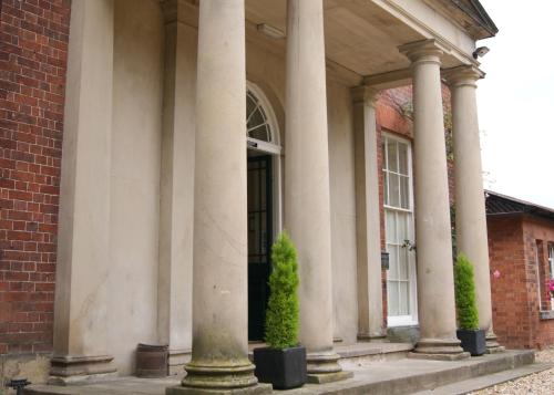 a building with columns and a door with a plant at Old Rectory in Wem