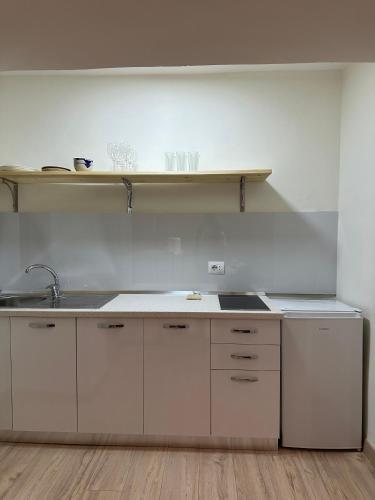 a kitchen with white cabinets and a sink and a shelf at White apartment, in the center of Tirana in Tirana