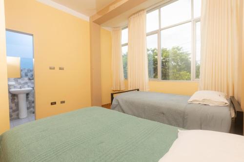 a bedroom with two beds and a window and a sink at Casa Grau 1590 in Tarapoto