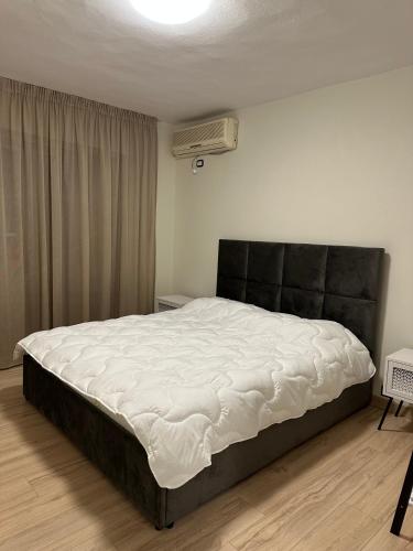 - une chambre avec un grand lit et une tête de lit noire dans l'établissement White apartment, in the center of Tirana, à Tirana