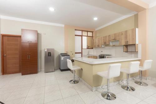 a large kitchen with white chairs and a counter at Casa Grau 1590 in Tarapoto