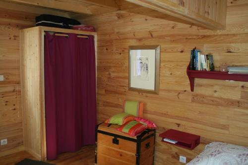 een slaapkamer met houten wanden en een paars gordijn bij Chaledhote in Écurolles