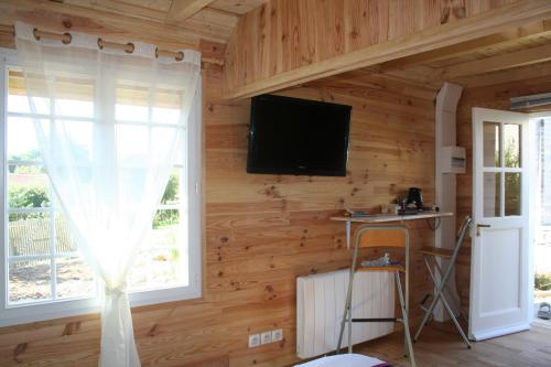 a room with a wooden wall with a television and a window at Chaledhote in Écurolles