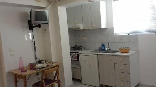 Ανεξάρτητο διαμέρισμα κοντά στο κέντρο της πάτρας في باترا: مطبخ مع حوض وتلفزيون على الحائط