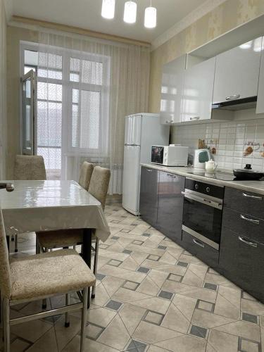 a kitchen with a table and a white refrigerator at Apartment Mangilik El in Prigorodnyy