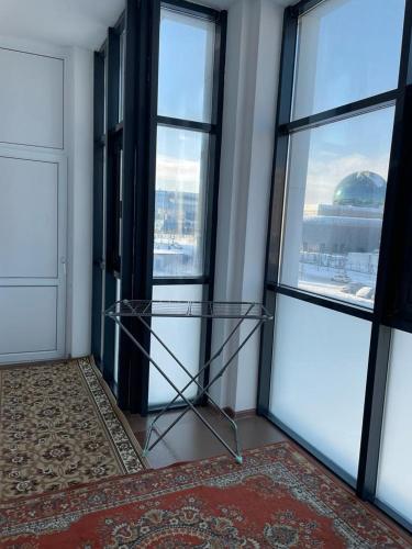 szklana półka w pokoju z dwoma oknami w obiekcie Apartment Mangilik El w mieście Prigorodnyy