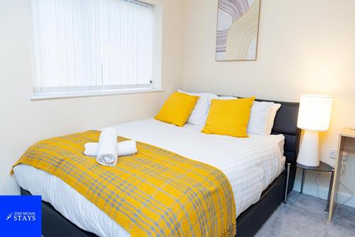 a bedroom with a large bed with yellow pillows at 2ndHomeStays-West Bromwich- 2-Bedroom Maisonette in West Bromwich