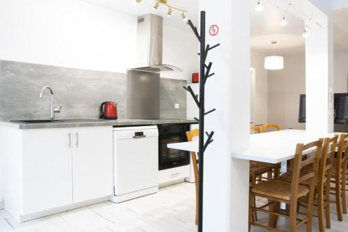 una cocina con armarios blancos y una mesa con sillas. en "Peace & love house" en campagne de Poitiers en Montamisé
