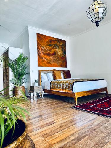 a bedroom with a bed and a painting on the wall at La Plage Onirique Beachfront Nusa Penida in Nusa Penida