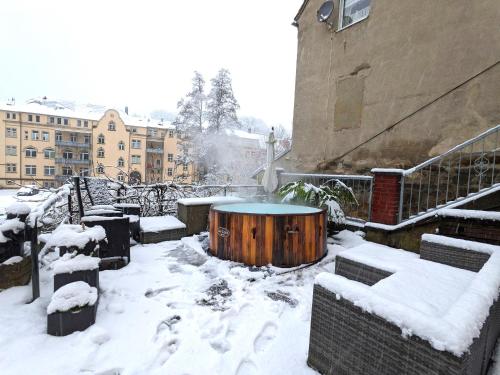 een sneeuwbedekte tuin met een tafel en gebouwen bij Urlaubsmagie - Garten, Whirlpool, Sauna - UO2 in Sebnitz