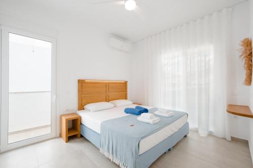 a white bedroom with a bed and a large window at Villa Marina Hills in Makry Gialos