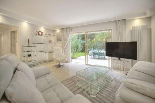 sala de estar con sofá blanco y TV en Rocher Saint Georges spacieux 3P jardin piscine, en Cannes