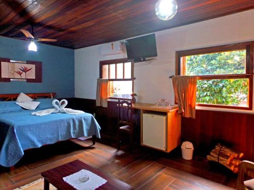 a bedroom with a bed and a table and a window at Hotel Cantinho de Férias in Visconde De Maua