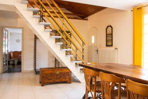 uma sala de jantar com uma mesa de madeira e escadas em Le gîte campagnard à 10 min de Poitiers em Migné-Auxances