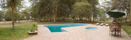 una piscina con sombrilla en un parque en NSYA CAMP MANYARA en Mto wa Mbu