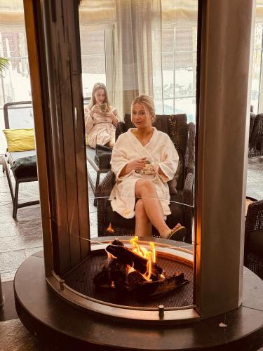 a woman sitting in a chair in front of a fire at Vakantiehotel Der Brabander in Winterberg