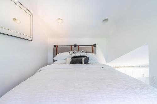 a white bedroom with a bed with white sheets at Cute as a Button! in Seattle