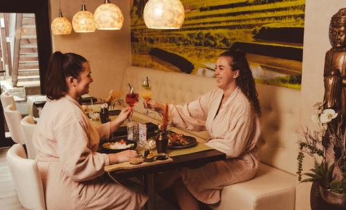 two women sitting at a table with glasses of wine at Vakantiehotel Der Brabander in Winterberg