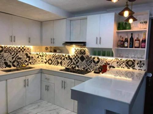 uma cozinha com armários brancos e azulejos pretos e brancos em Heart of Paete Laguna, Camarero Transient House em Paete