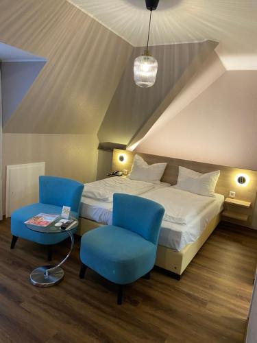 a bedroom with a bed and two blue chairs at Hotel Feldmann in Münster