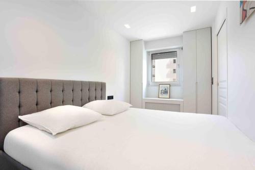 1 dormitorio blanco con 1 cama blanca grande y 2 almohadas en Superbe appartement refait au centre de Clamart, en Clamart