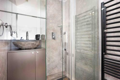 Un baño con lavabo y ducha de cristal. en Superbe appartement refait au centre de Clamart, en Clamart