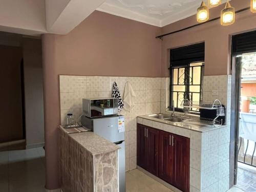 a kitchen with a sink and a microwave at Sanz Cozy Stay; Butenga Estate, Kira. in Kira