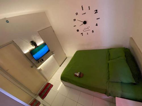 Cette chambre comprend un lit et une horloge murale. dans l'établissement Aeropolis Apartemen, à Teko