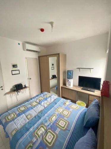 a bedroom with a bed and a desk with a television at Aeropolis Apartemen in Teko