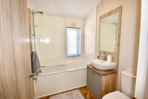 a bathroom with a sink and a tub and a toilet at Rowan a welcoming countryside lodge in Ryde