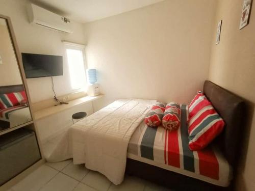 una camera da letto con un letto con cuscini rossi e bianchi di Aeropolis Apartemen a Teko