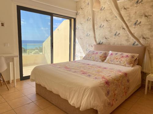 a bedroom with a bed with a view of the ocean at Casa das Pedras Pretas in Porto Santo