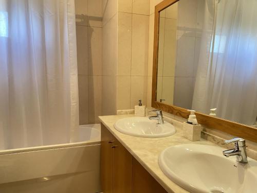 a bathroom with two sinks and a tub and a mirror at Casa das Pedras Pretas in Porto Santo