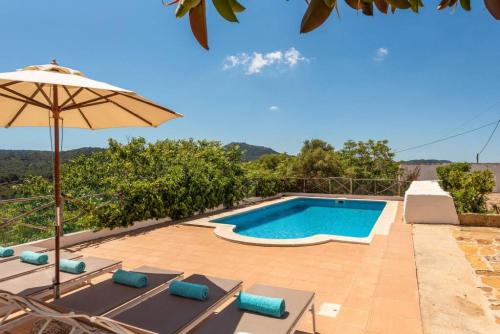 a swimming pool with lounge chairs and an umbrella at Finca BellaMirada in Es Mercadal
