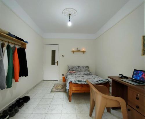 a bedroom with a bed and a desk with a laptop at Kemet - a private room at Shared apartment For Men only No Ladies allowed غرفة خاصة في شقة مشتركة للرجال فقط ممنوع السيدات in Alexandria