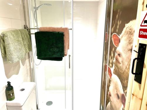 a bathroom with a shower with a cow picture on the wall at The Walkers' Cwtch in Ffestiniog