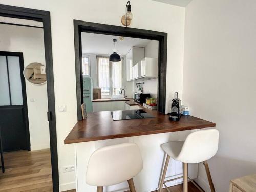 - une cuisine avec un comptoir et 2 chaises blanches dans l'établissement Appartement refait à neuf à 2 min du Chateau, à Versailles