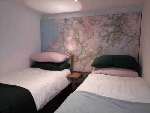 two beds in a room with a map on the wall at The Walkers' Cwtch in Ffestiniog