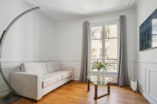 un salon avec un canapé blanc et une table en verre dans l'établissement Le XVIe Chic - Paris, à Paris