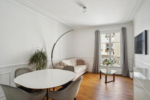 un salon blanc avec une table et des chaises blanches dans l'établissement Le XVIe Chic - Paris, à Paris