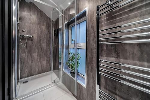 a bathroom with a shower with a window and a plant at The Eden Loft: A Stylish Retreat in Strabane