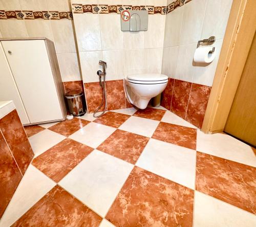 a bathroom with a toilet and a checkered floor at 2 Zimmer, Garten, Terrasse, Bad mit Dusche und WC und Gemeinschaftsküche in Ilsede