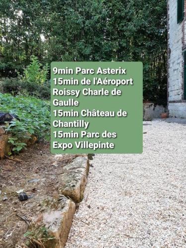 un panneau dans un jardin à côté d'une cour dans l'établissement Résidence du Houx - 1 (Astérix, Aéroport CDG, Chantilly, Parc des expos...), à Survilliers