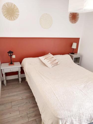 een slaapkamer met een wit bed en 2 tafels bij Maison 10min à pied de la plage in Saint-Cyprien