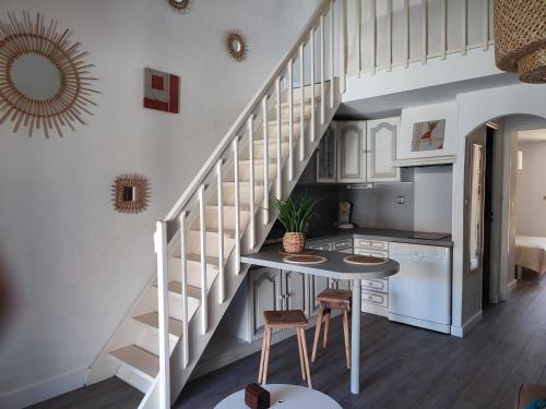 una cocina con una escalera con mesa y sillas en Maison 10min à pied de la plage en Saint-Cyprien