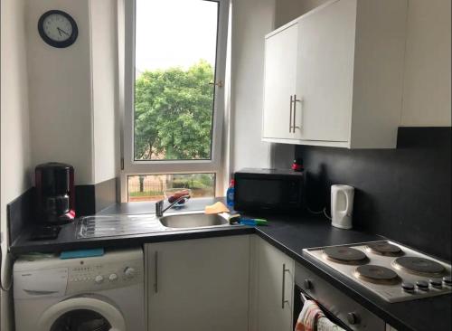 a kitchen with a sink and a washing machine at Cosy, large double room in a shared flat in Edinburgh