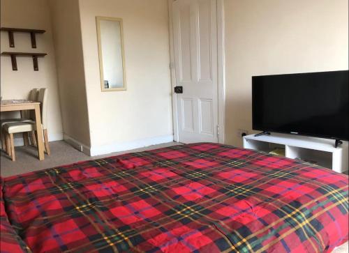 a bedroom with a bed and a flat screen tv at Cosy, large double room in a shared flat in Edinburgh